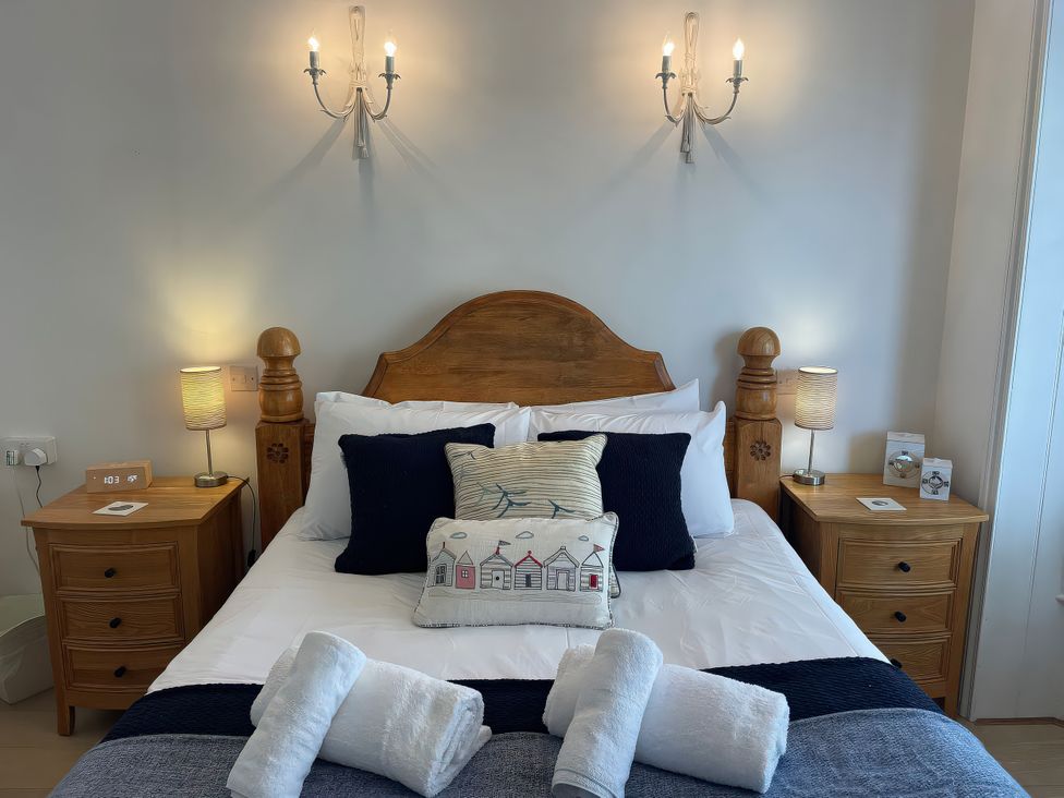 A bedroom with a wooden bed and bedside tables at Seahorse Cottage in Weymouth