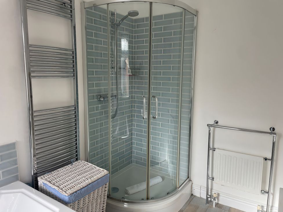 A bathroom featuring a shower with glass doors and a towel rack at Seahorse Cottage in Weymouth