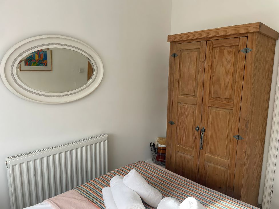 A bedroom with a wardrobe and mirror at Seahorse Cottage in Weymouth