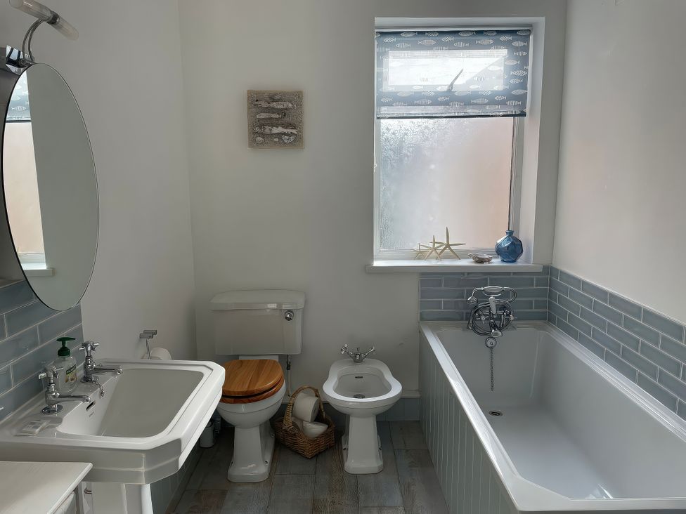 A bathroom with a sink, toilet, and bathtub at Seahorse Cottage in Weymouth