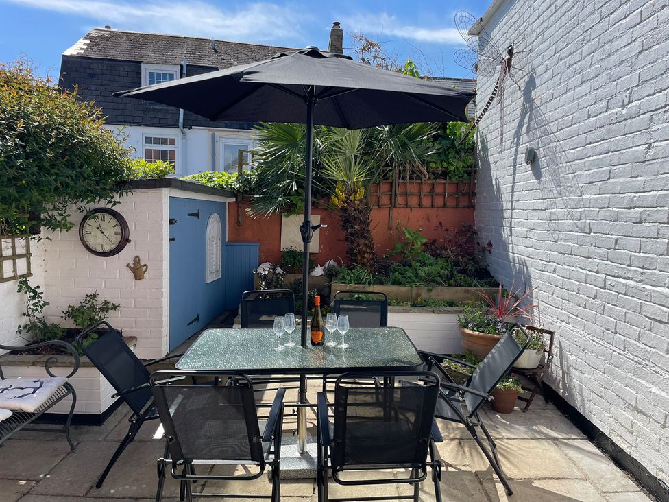 A garden with a table and chairs under an umbrella at Seahorse Cottage Weymouth