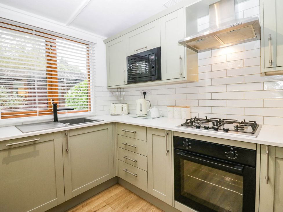A kitchen with a sink, stove, microwave, and kettle at Terabitha Lodge in Troutbeck