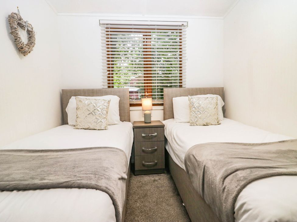 A bedroom with two beds and a nightstand at Terabitha Lodge in Troutbeck