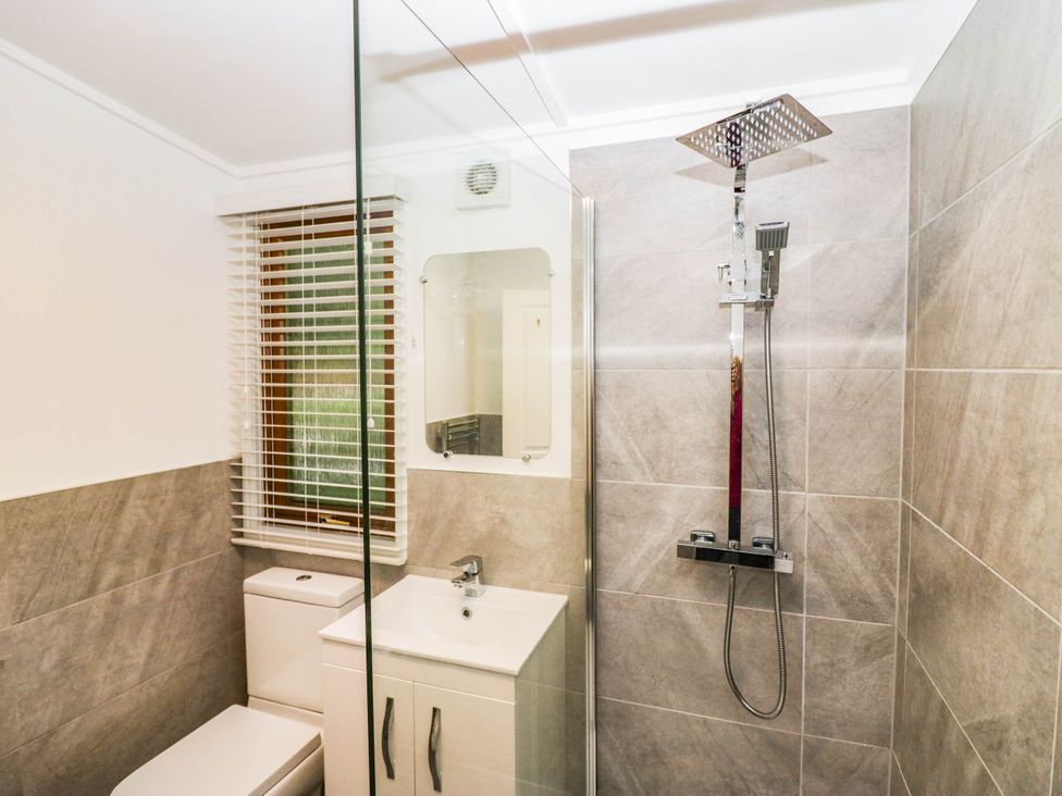 A bathroom featuring a shower, toilet, sink, and window at Terabitha Lodge in Troutbeck
