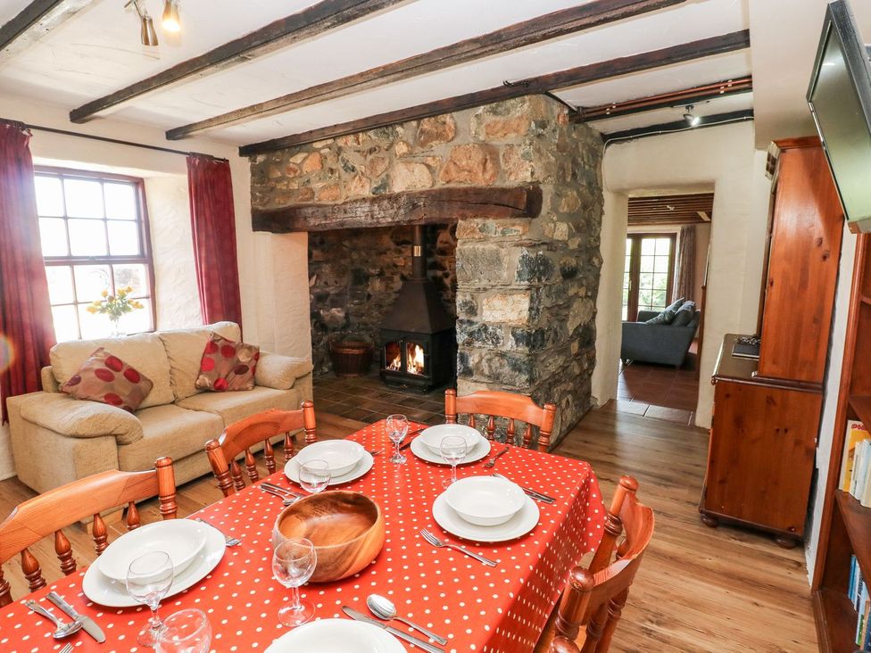 A dining room with a table and chairs near a fireplace at Ty Fferm in Newport