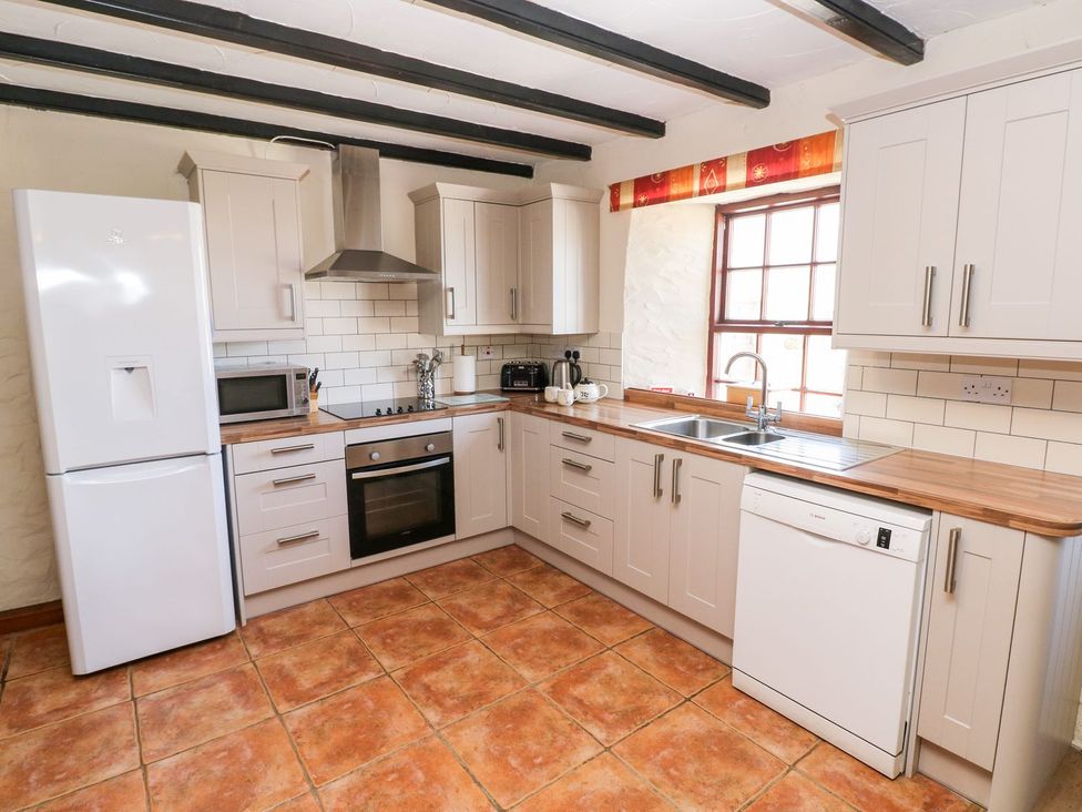 A kitchen with a refrigerator, oven, sink, and cabinets at Ty Fferm Newport