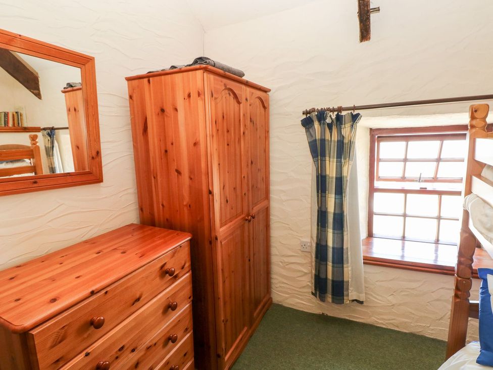 A bedroom with a wardrobe, chest of drawers, and a window at Ty Fferm in Newport