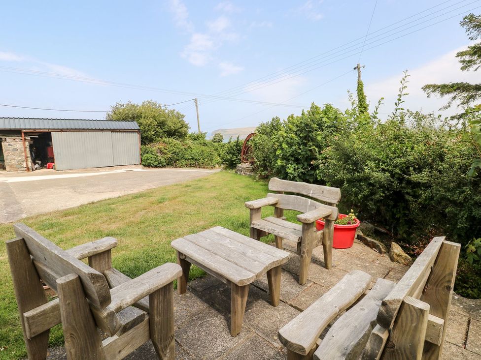 A garden with wooden seating and a shed at Ty Fferm Newport
