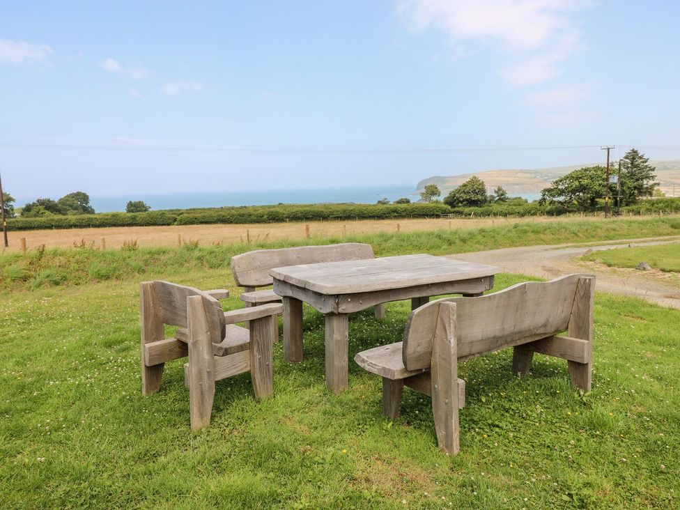 A table and benches overlooking a field and the ocean at Ty Fferm in Newport