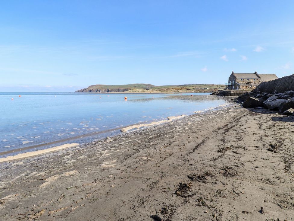 A beach with water and a house at Ty Fferm in Newport