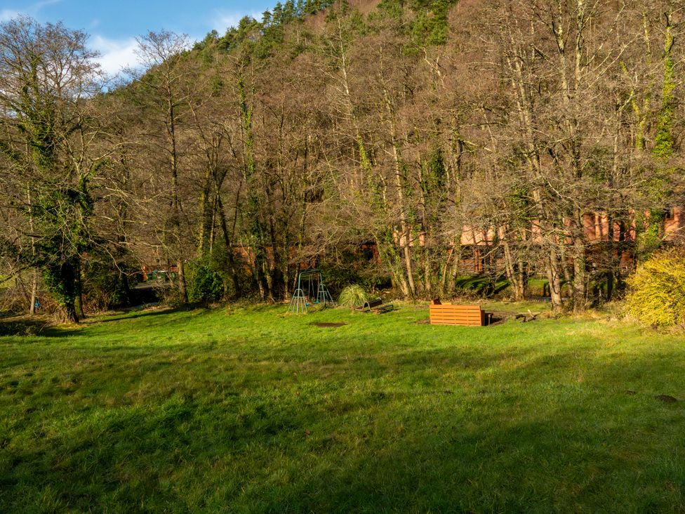 A garden with trees and a swing set at 2 bedroom Cabin No.1 Port Talbot