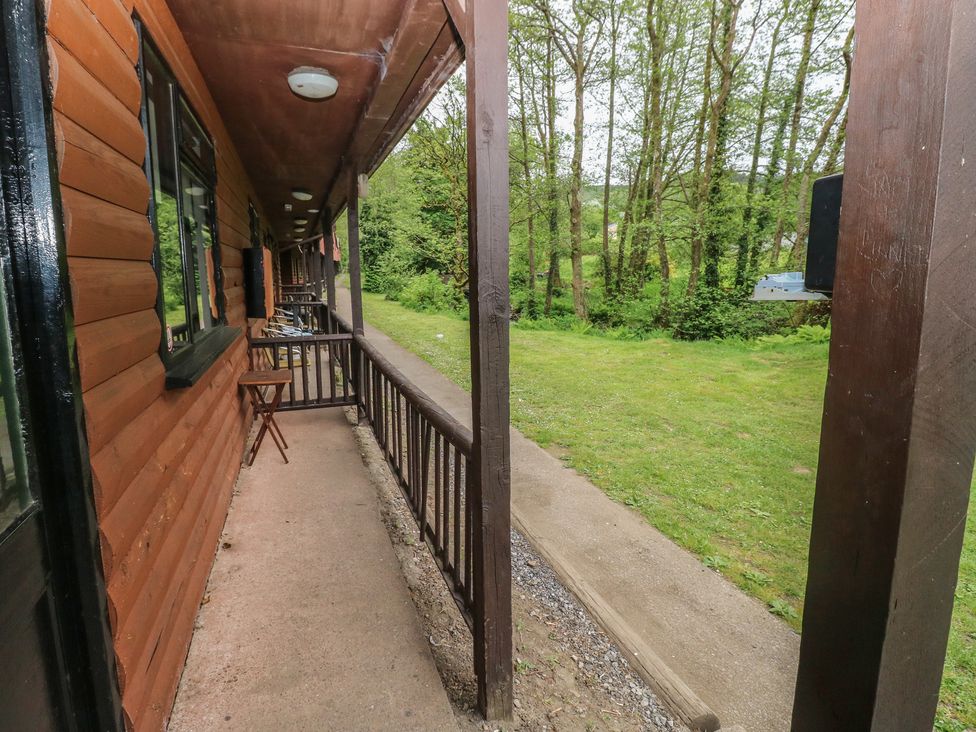 An outdoor area with a wooden railing and chairs at Cabin No. 13 - Salt and Fern Cabins Goytre near Port Talbot