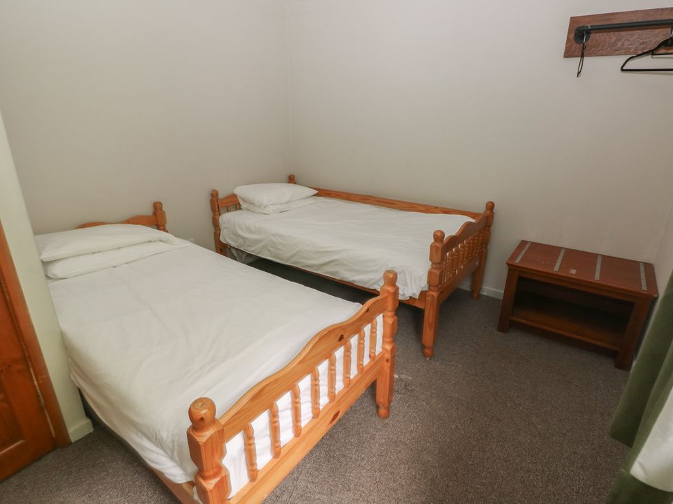 A bedroom with two single beds and a wooden table at Cabin No. 13 - Salt and Fern Cabins Goytre near Port Talbot