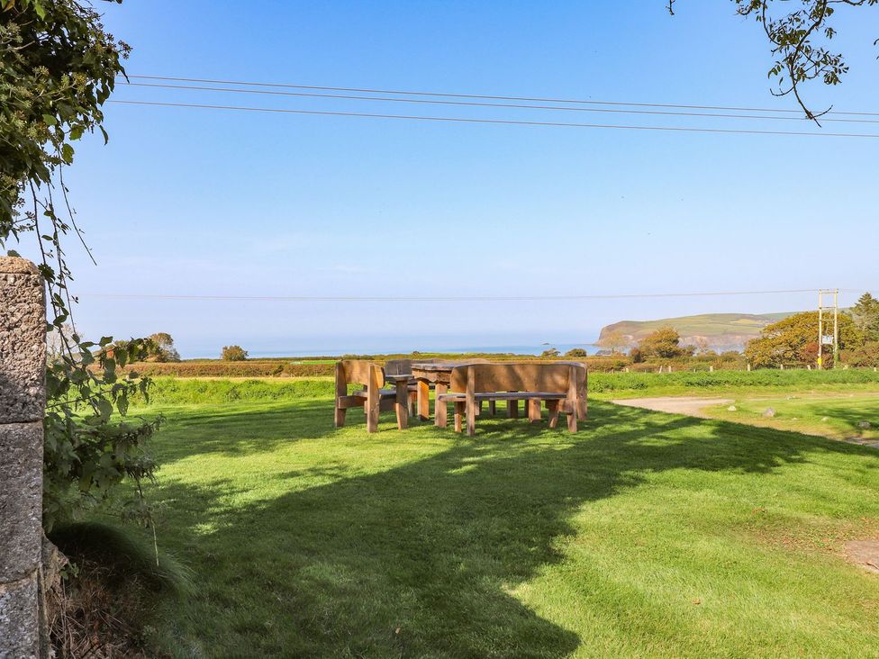 An outdoor seating area with a table and chairs overlooking the ocean at Ty Felin Newport