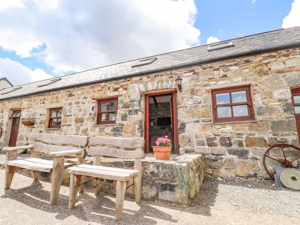 An outdoor area with wooden chairs and stone wall at Ty Felin Newport
