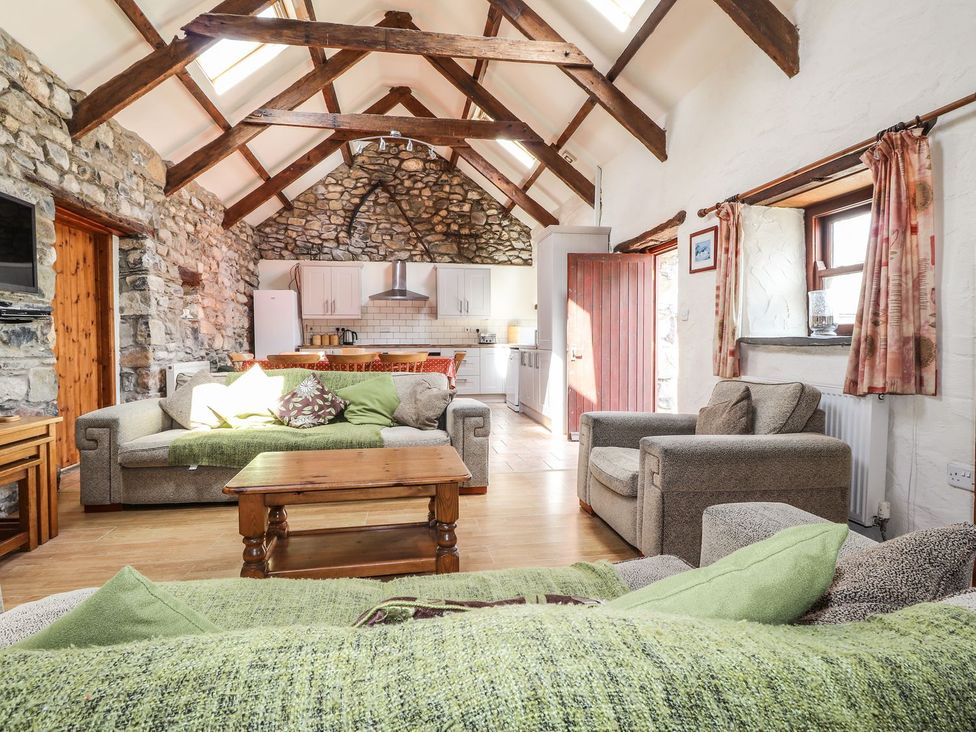 A living room with a sofa and a kitchen area at Ty Felin in Newport