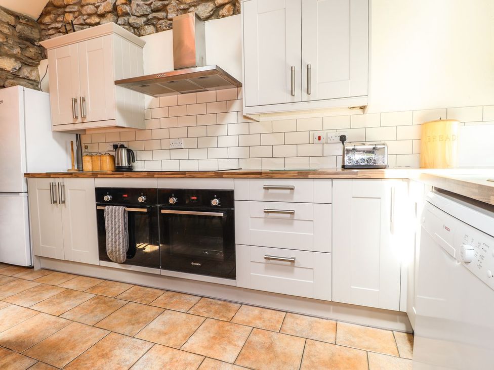 A kitchen with cabinets, oven, toaster, and refrigerator at Ty Felin Newport