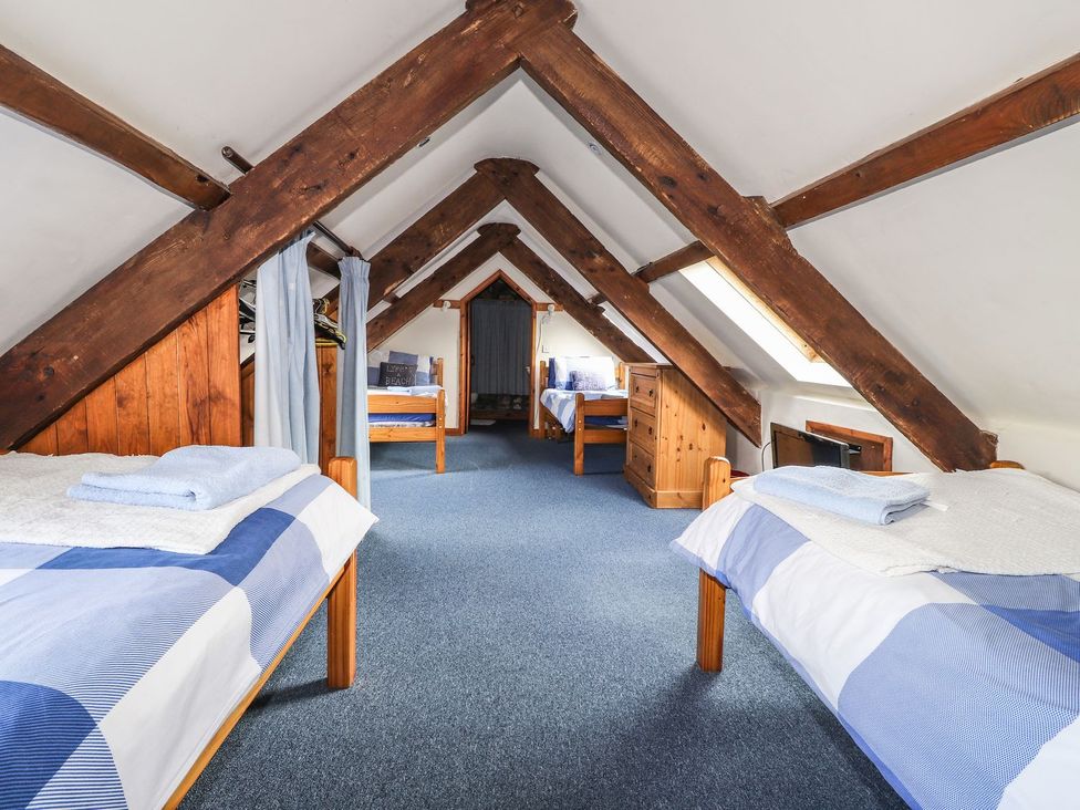 A bedroom with multiple beds and a dresser at Ty Felin Newport