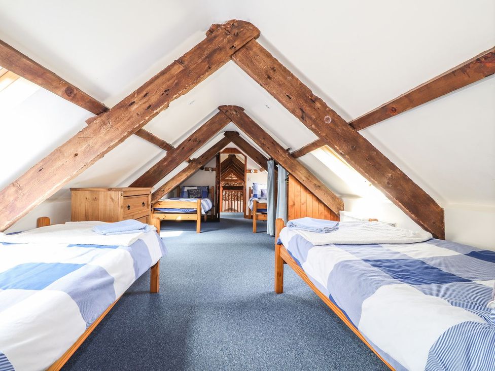 An attic with beds and wooden beams at Ty Felin Newport