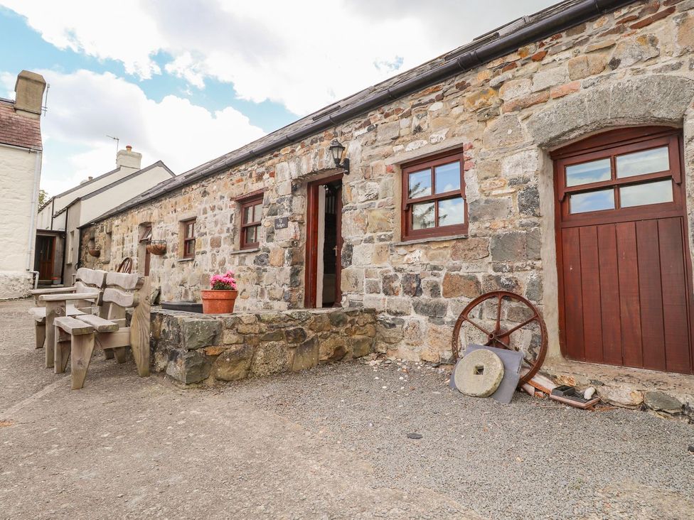 An outdoor area with stone building and wooden chairs at Ty Felin Newport