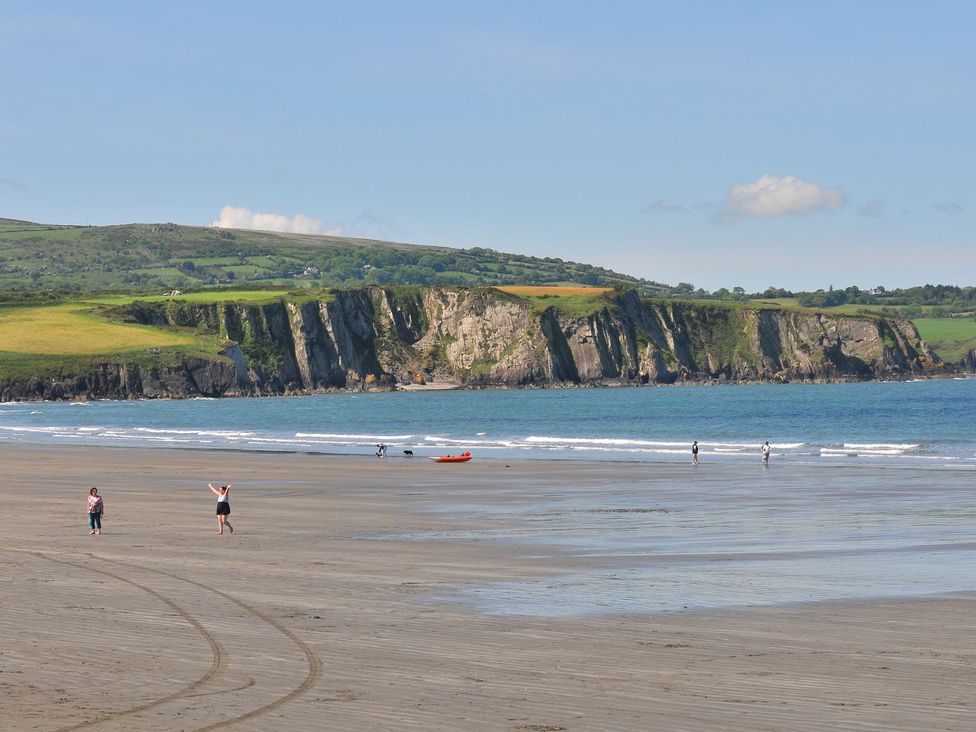 A beach with cliffs and people enjoying the water at Ty Felin in Newport