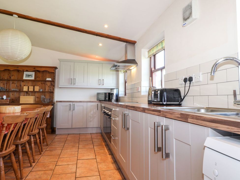 A kitchen with cabinets, dining table, and appliances at Ty Gwartheg in Newport
