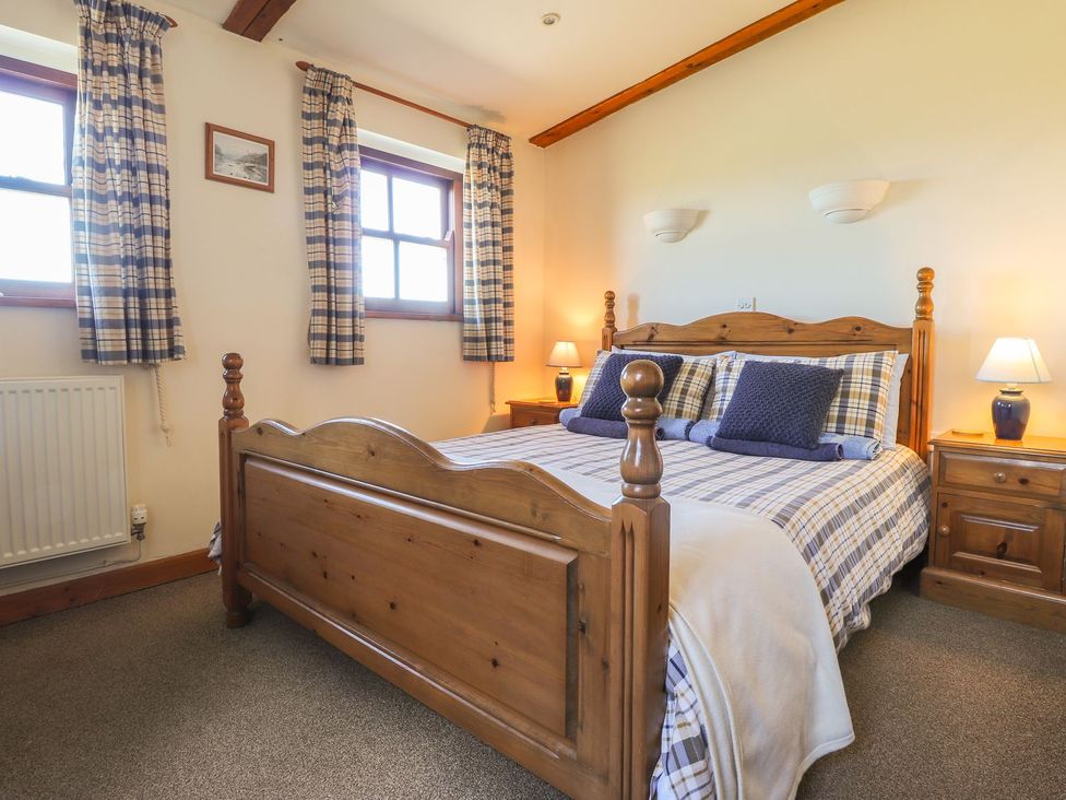 A bedroom with a wooden bed and nightstands at Ty Gwartheg Newport