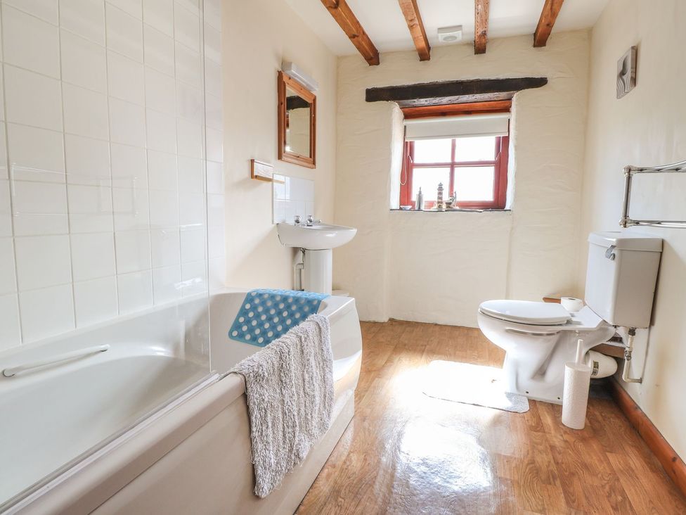 A bathroom with a bathtub, toilet, sink and window at Ty Gwartheg Newport