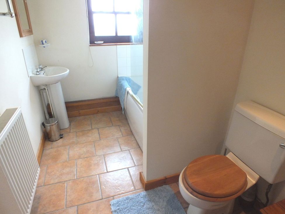 A bathroom with a sink, toilet, bathtub, and a radiator at Ty Cariad Newport