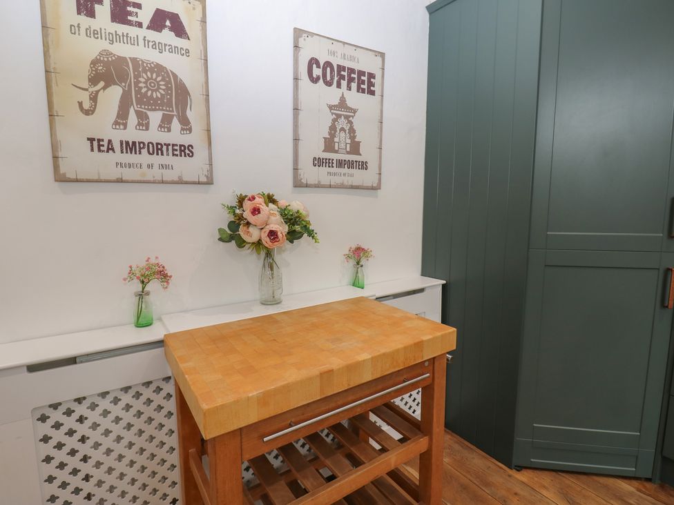 A kitchen with a wooden table and posters at Broadwath Old House in Heads Nook