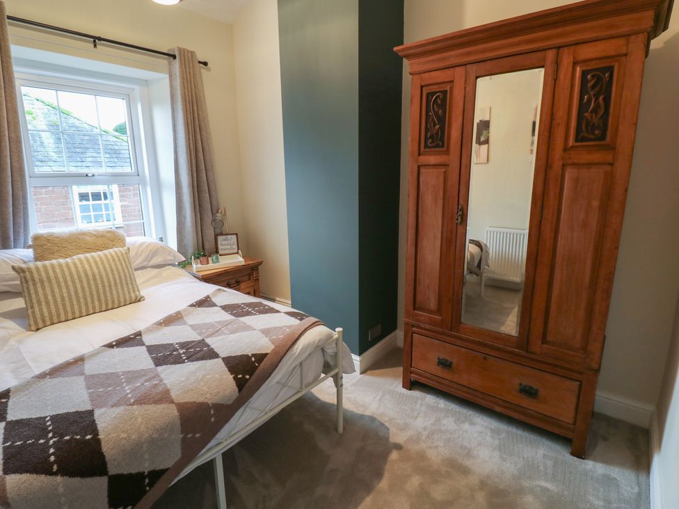 A bedroom with a bed and wooden wardrobe at Broadwath Old House in Heads Nook