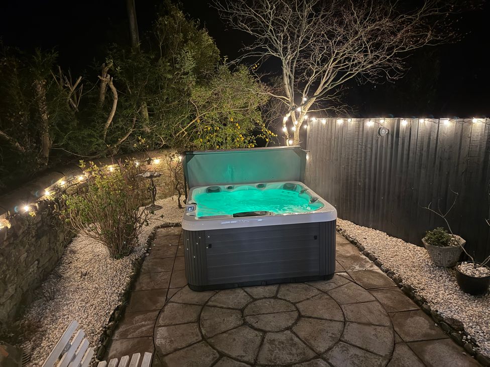 An outdoor space with a hot tub surrounded by patio stones and fairy lights at Broadwath Old House, Broadwath near Corby Hill