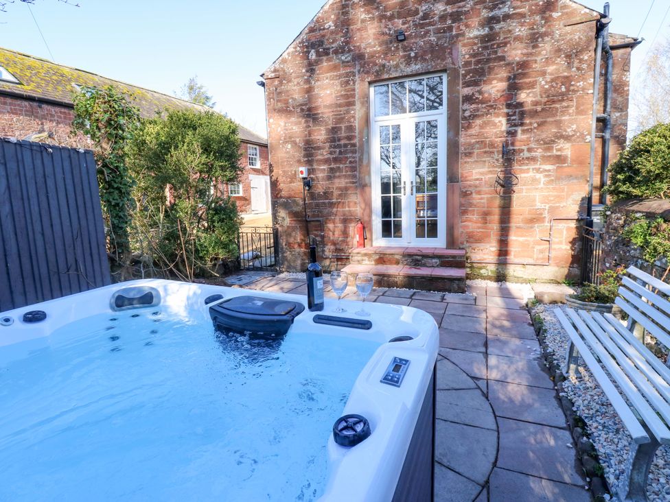 An outdoor area with a hot tub and patio at Broadwath Old House near Corby Hill