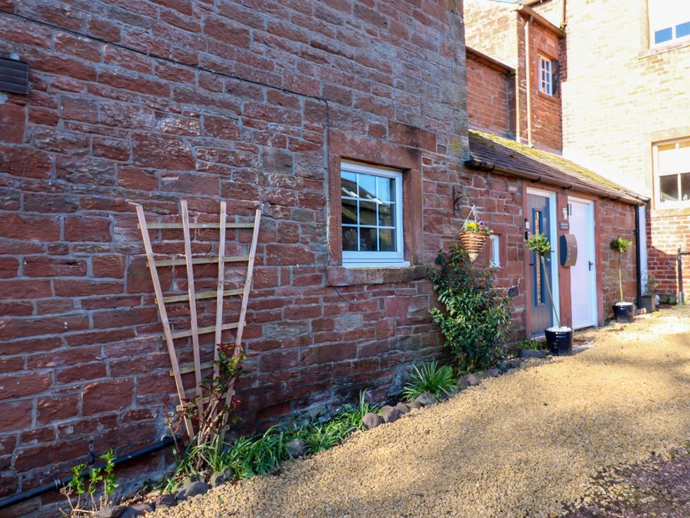 An outdoor area with a stone wall and plants at Broadwath Old House near Corby Hill