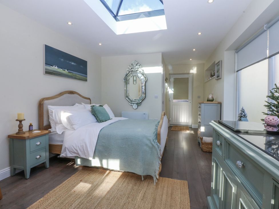 A bedroom with a bed and a mirror at The Summerhouse in Llandudno