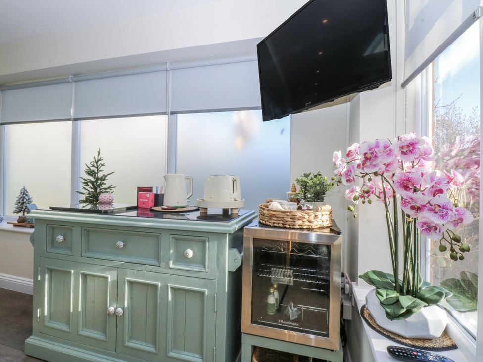A kitchen with a cabinet and flowers at The Summerhouse in Llandudno