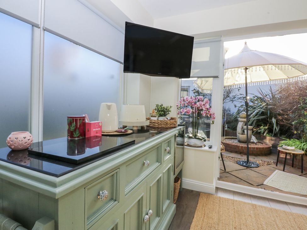 A room with a cabinet and television with outdoor seating at The Summerhouse in Llandudno