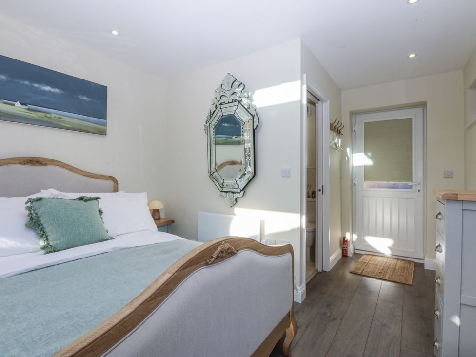 A bedroom with a bed and a mirror at The Summerhouse in Llandudno
