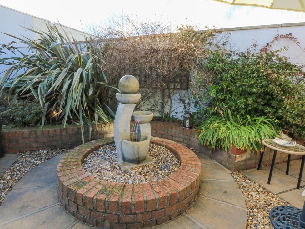 A garden with a water fountain and surrounding plants at The Summerhouse in Llandudno