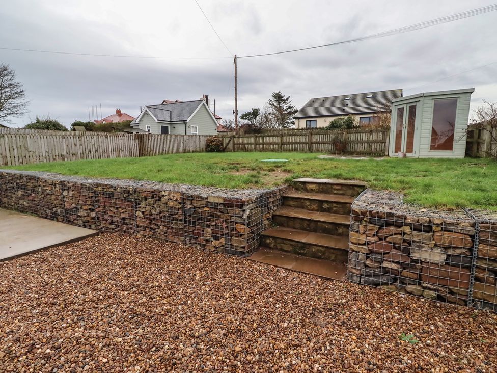A garden with a stone wall and steps at Braeburn in Bamburgh