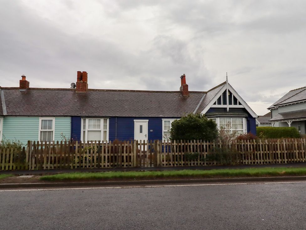 A house with a blue and green exterior and a picket fence at Braeburn in Bamburgh