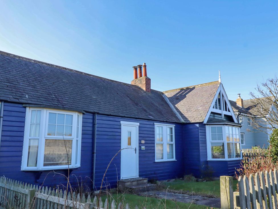 A house with blue exterior and a fence at Braeburn in Bamburgh