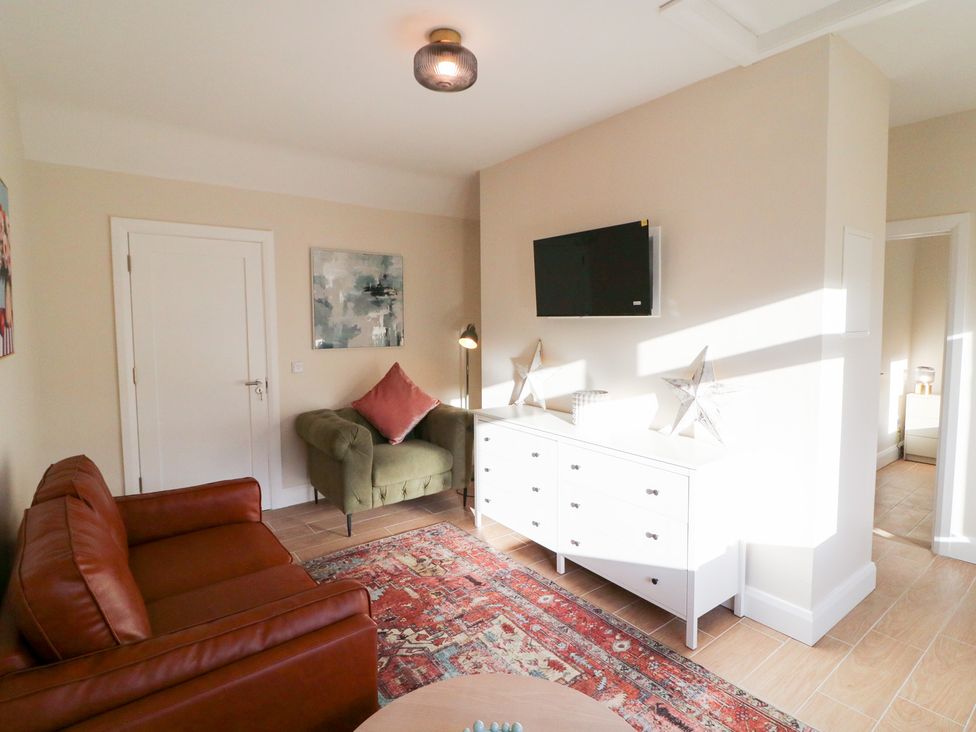 A living room with a sofa, armchair, and television at Duck Cottage