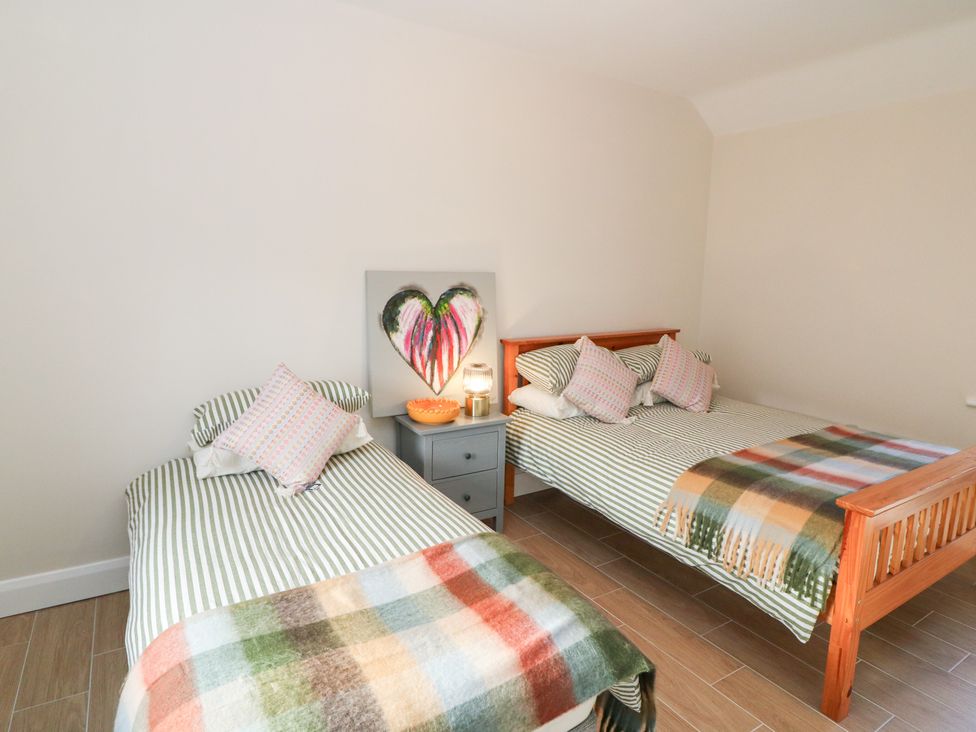 A bedroom with two beds and a nightstand at Duck Cottage