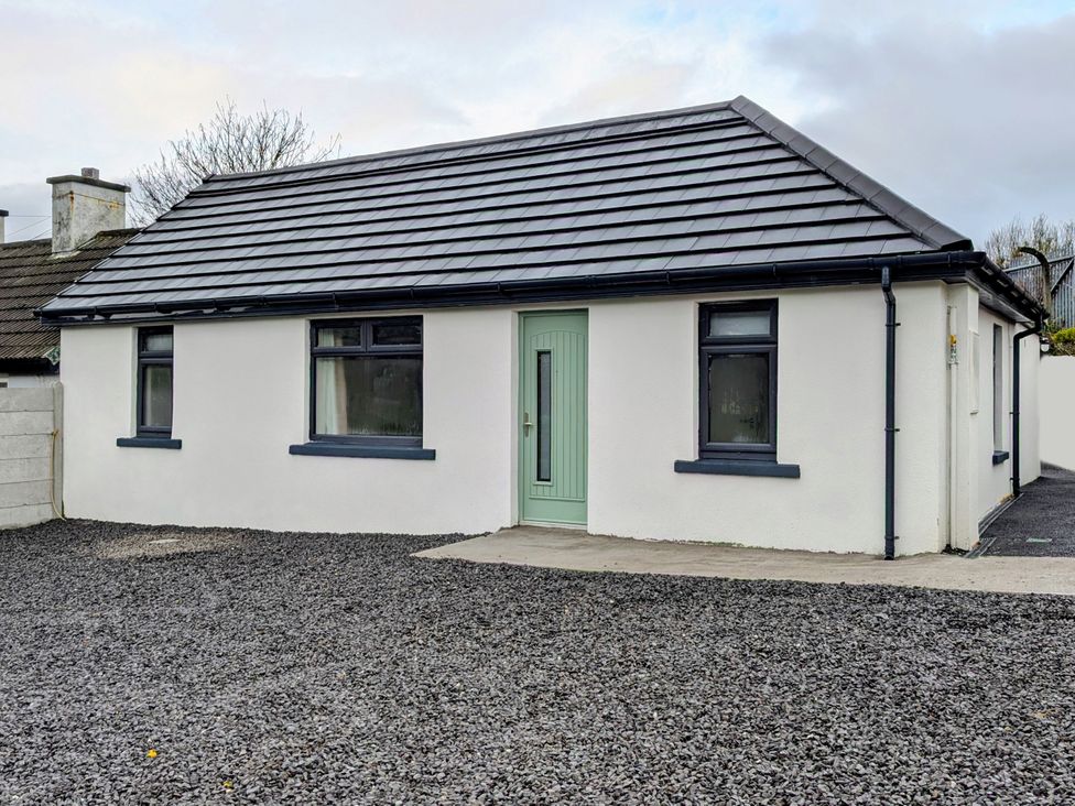 A house with a green door and gravel driveway at Duck Cottage in Caherciveen, County Kerry