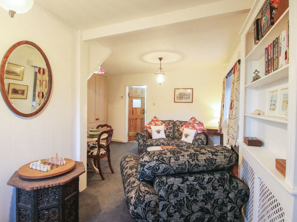 A living room with a sofa and bookshelves at Bumble Bee at 2 Clematis Cottage near Clee Hill