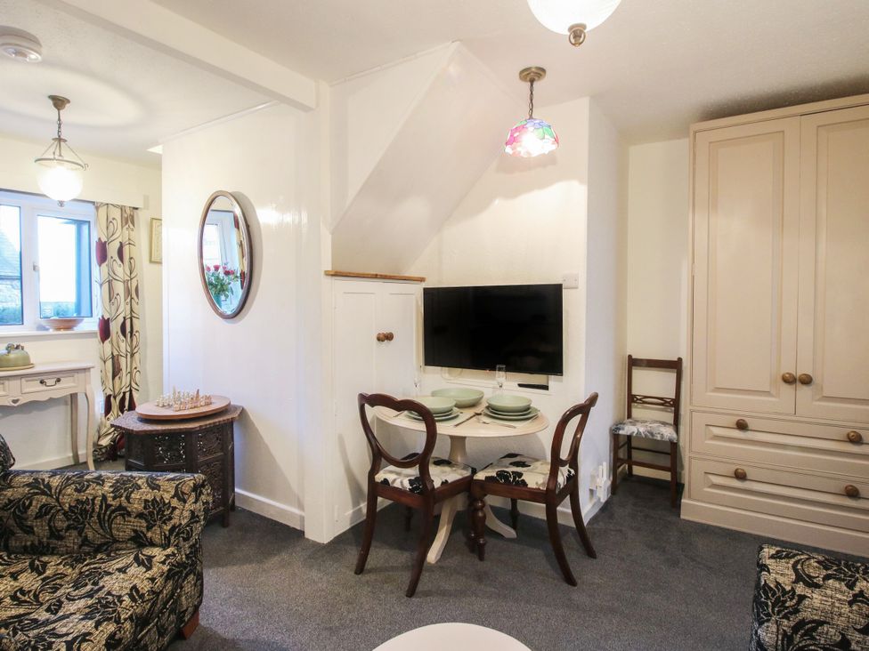 A living room with a dining table and television at Bumble Bee at 2 Clematis Cottage near Clee Hill