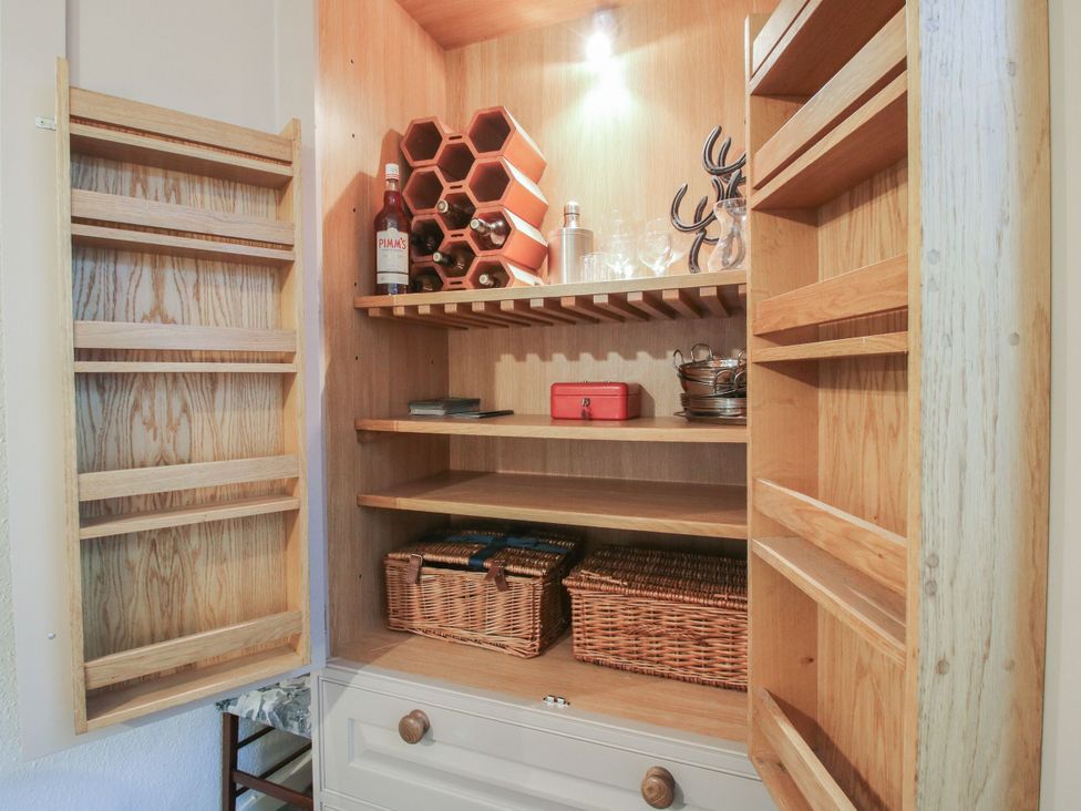 A pantry with wooden shelves and storage baskets at Bumble Bee at 2 Clematis Cottage near Clee Hill