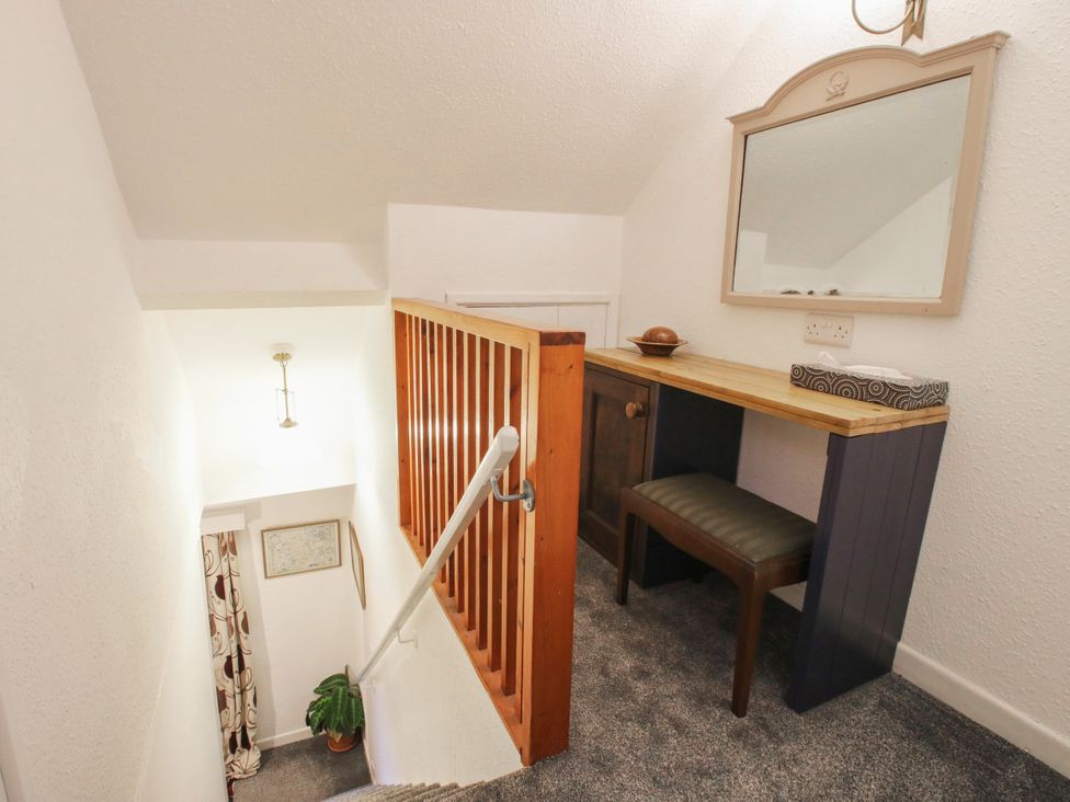 A hallway with a desk, mirror, and staircase at Bumble Bee at 2 Clematis Cottage near Clee Hill