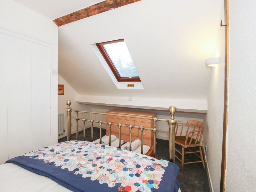 A bedroom with a bed, drawer, and chair at Bumble Bee at 2 Clematis Cottage near Clee Hill